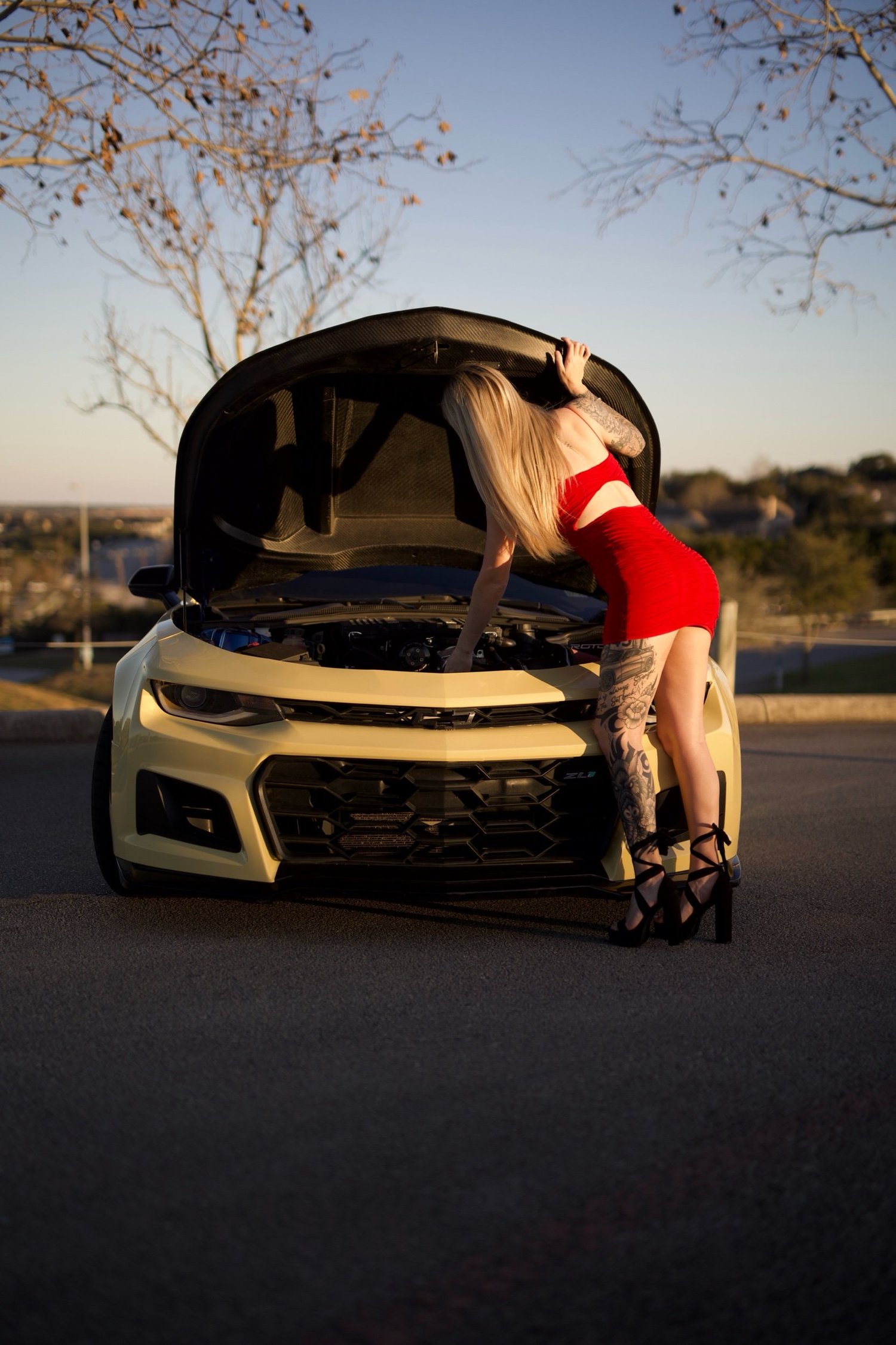 Alexxis in a red dress under the hood of the ZL1